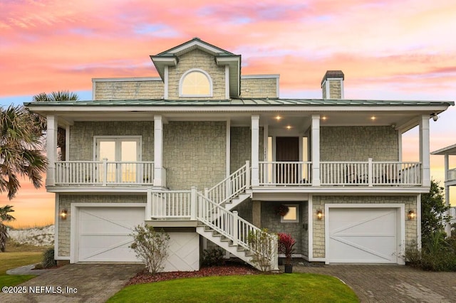 view of front of home featuring a garage, decorative driveway, covered porch, and stairway