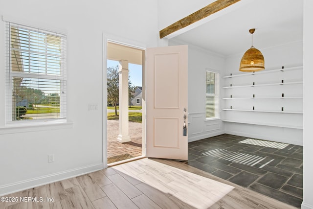 foyer featuring crown molding, decorative columns, baseboards, and wood finished floors