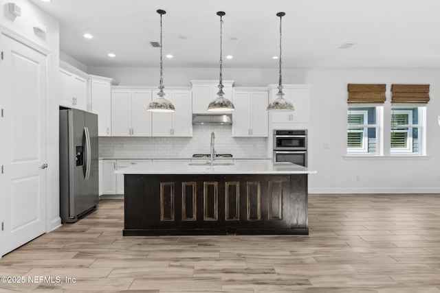 kitchen featuring stainless steel appliances, tasteful backsplash, light countertops, and range hood