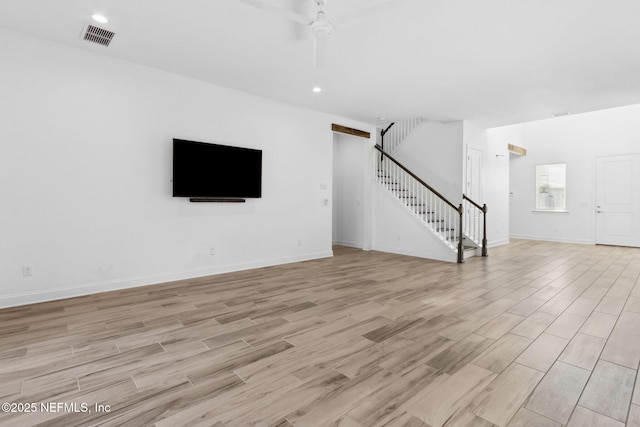 unfurnished living room featuring stairs, baseboards, visible vents, and light wood-style floors