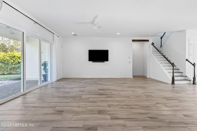 unfurnished living room featuring stairs, baseboards, a ceiling fan, and light wood-style floors