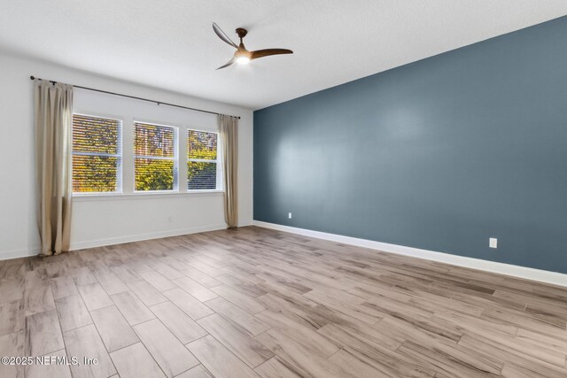 spare room featuring a ceiling fan, baseboards, and wood finished floors