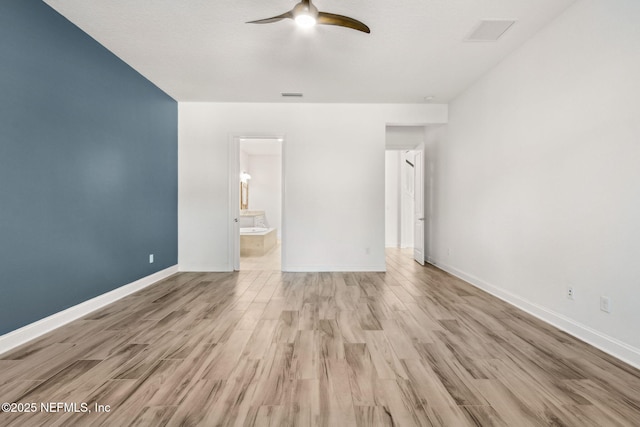 unfurnished bedroom with visible vents, connected bathroom, baseboards, and wood finished floors