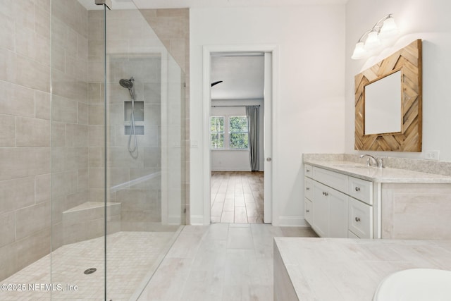 bathroom with wood finished floors, walk in shower, vanity, and baseboards