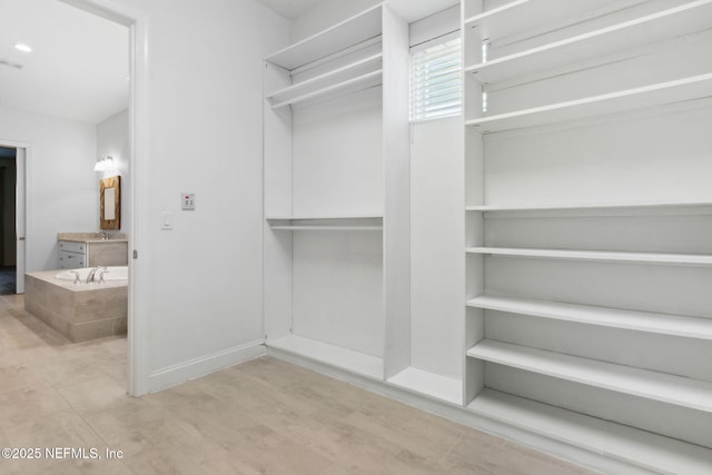 walk in closet featuring a sink and wood finished floors