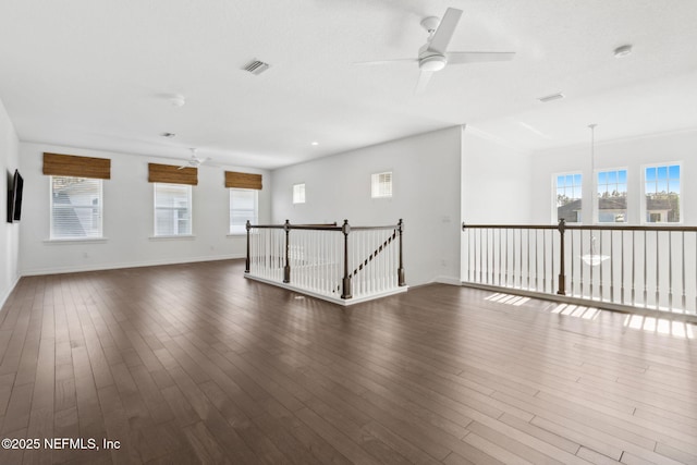 unfurnished room with plenty of natural light, dark wood finished floors, baseboards, and ceiling fan