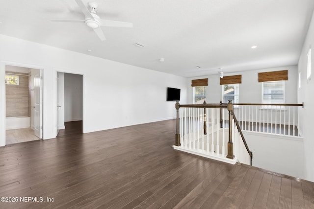 spare room with baseboards, plenty of natural light, a ceiling fan, and wood finished floors