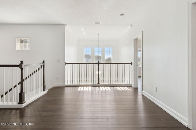 empty room featuring ornamental molding, dark wood-type flooring, visible vents, and baseboards