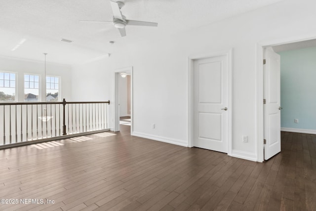 spare room featuring dark wood finished floors, a ceiling fan, and baseboards