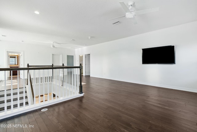 empty room with baseboards, ceiling fan, visible vents, and wood finished floors