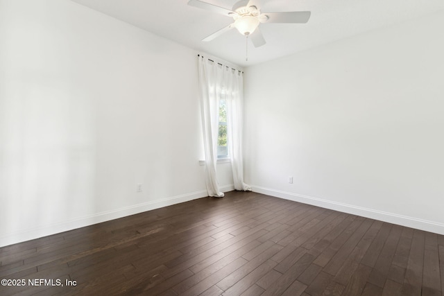 unfurnished room with dark wood-type flooring, a ceiling fan, and baseboards