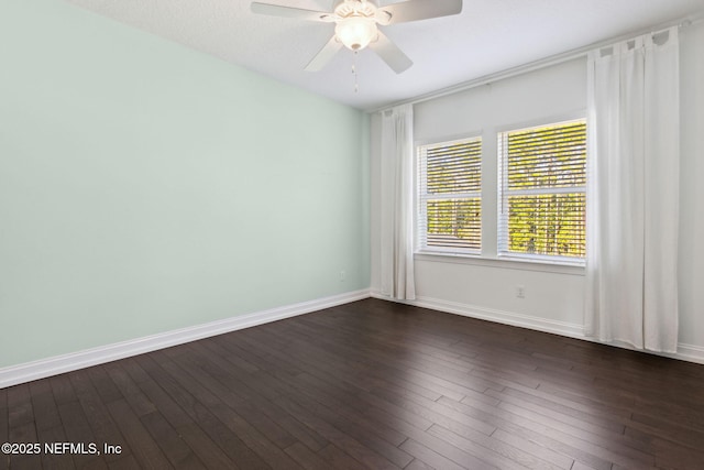 empty room featuring baseboards, dark wood finished floors, and a ceiling fan