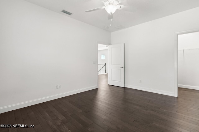 unfurnished room featuring baseboards, visible vents, and dark wood finished floors