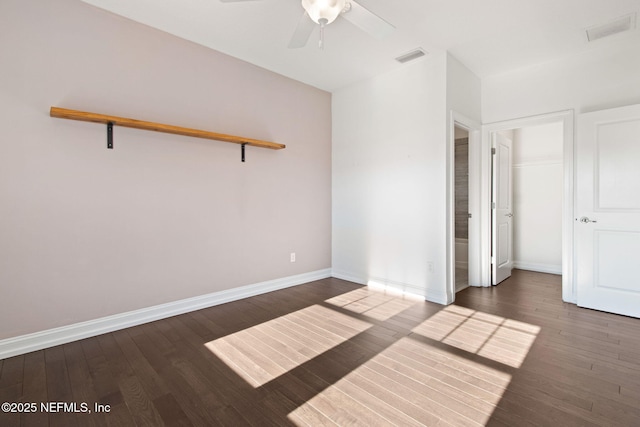 empty room with wood finished floors, visible vents, and baseboards