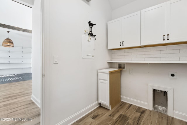 clothes washing area with baseboards, light wood finished floors, cabinet space, and hookup for an electric dryer