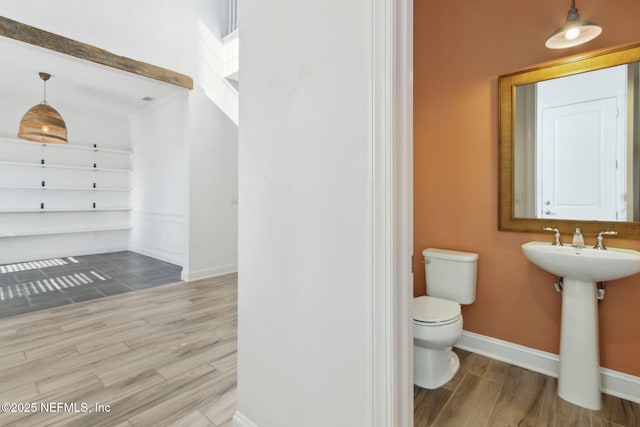 bathroom with a sink, wood finished floors, toilet, and baseboards