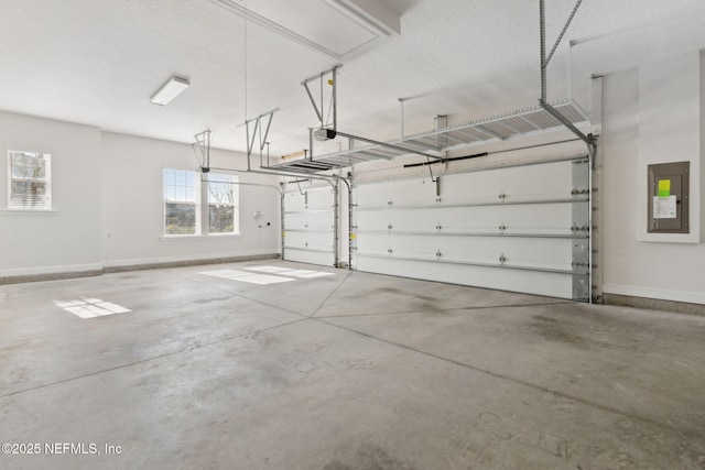 garage featuring a garage door opener, electric panel, and baseboards