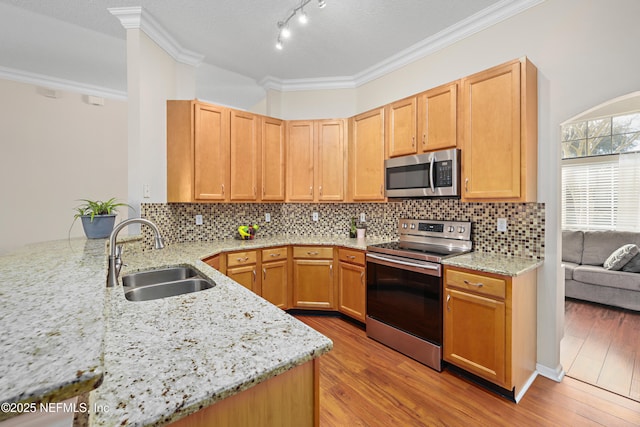 kitchen with a sink, stainless steel appliances, light stone counters, and light wood finished floors