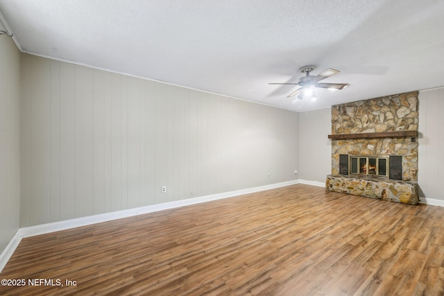 unfurnished living room with ceiling fan, a fireplace, hardwood / wood-style floors, and a textured ceiling