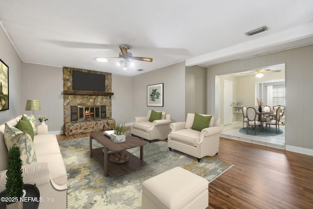 living room with a fireplace, wood-type flooring, ornamental molding, and ceiling fan