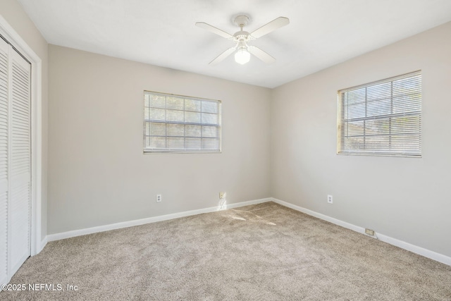 unfurnished bedroom featuring multiple windows, carpet flooring, ceiling fan, and a closet