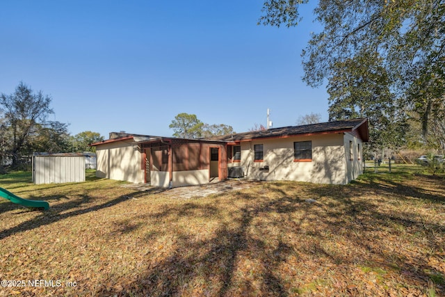 rear view of house featuring a storage shed and a lawn