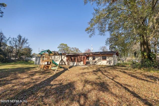 rear view of house featuring a lawn and a playground