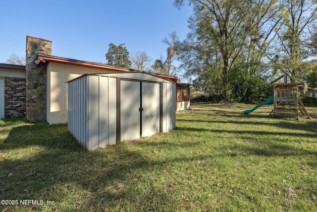 view of outdoor structure featuring a playground and a lawn