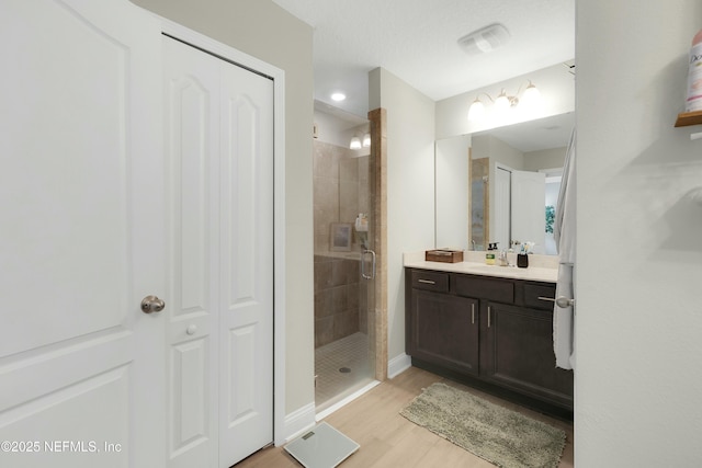 bathroom featuring vanity, hardwood / wood-style floors, and a shower with shower door