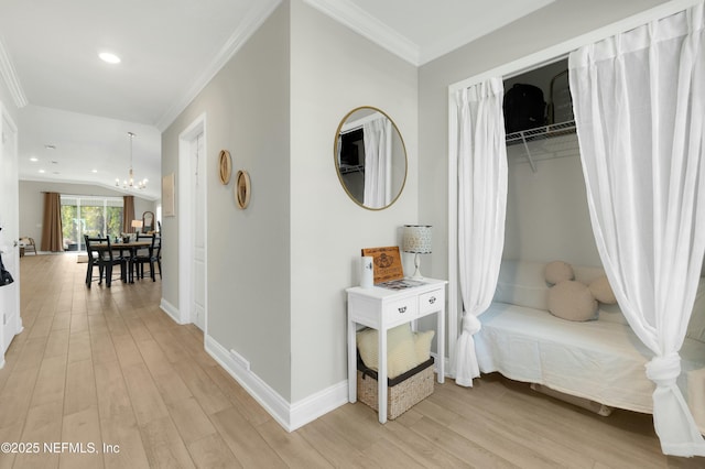 hall with crown molding, a chandelier, and light wood-type flooring