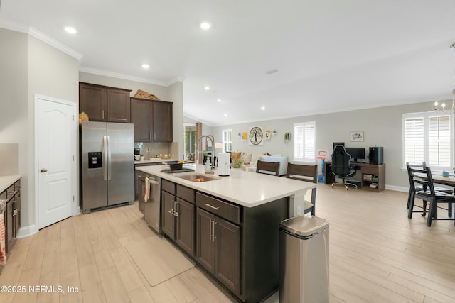 kitchen featuring sink, dark brown cabinetry, stainless steel appliances, a center island with sink, and light wood-type flooring