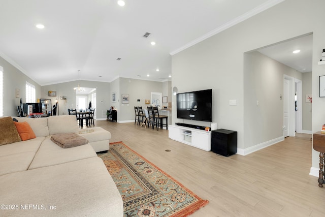 living room with lofted ceiling, crown molding, light hardwood / wood-style floors, and a chandelier