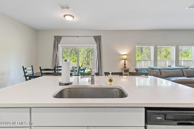 kitchen with white cabinetry, sink, light stone countertops, and black dishwasher