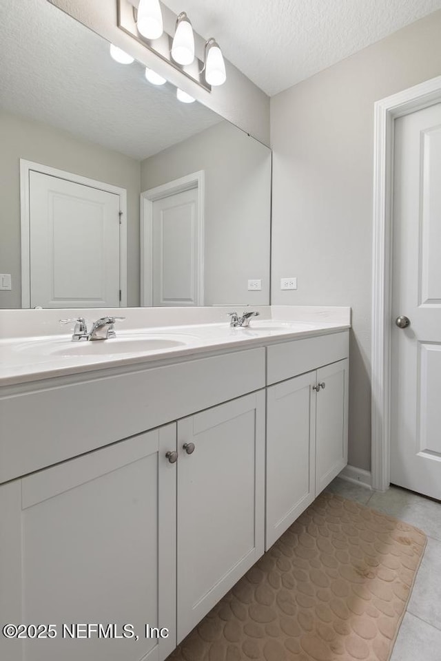 bathroom with tile patterned floors, vanity, and a textured ceiling