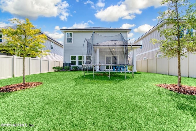 rear view of house featuring a trampoline and a lawn