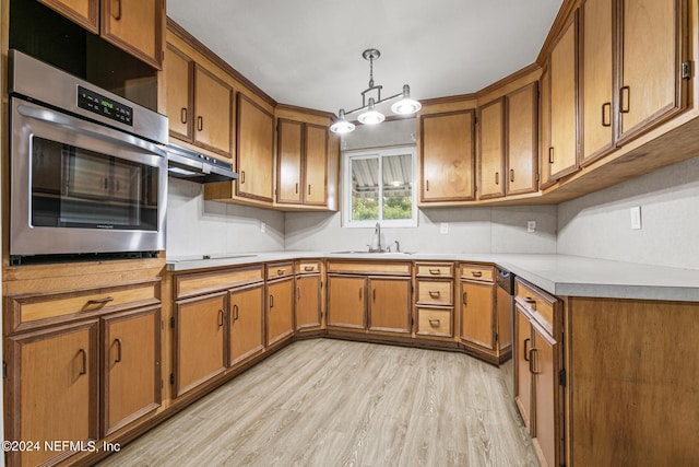 kitchen featuring sink, stainless steel oven, decorative light fixtures, light wood-type flooring, and black electric stovetop