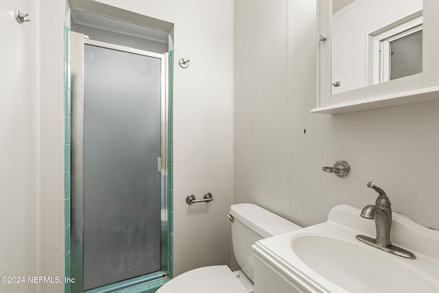 bathroom featuring toilet, a shower with shower door, and sink