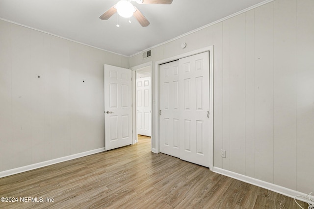 unfurnished bedroom featuring ornamental molding, ceiling fan, light wood-type flooring, and a closet