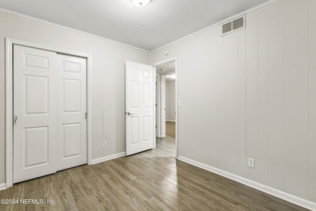 unfurnished bedroom with wood-type flooring and ornamental molding