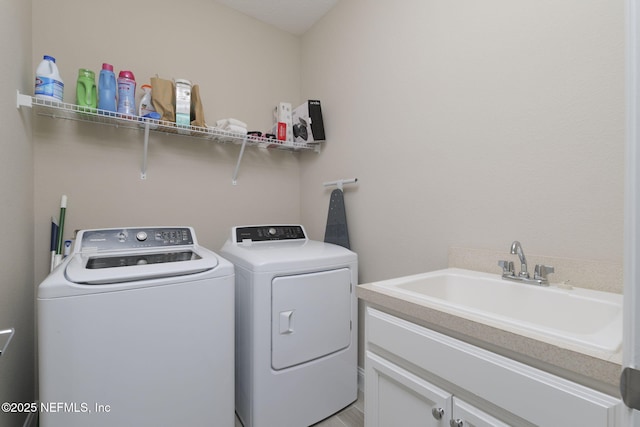 laundry room featuring cabinets, sink, and separate washer and dryer