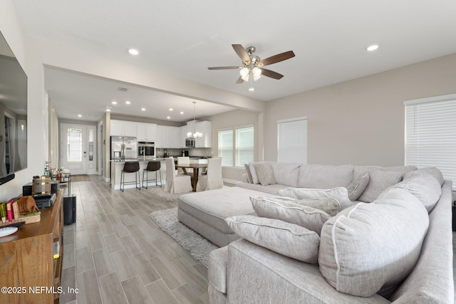 living room featuring ceiling fan with notable chandelier and light hardwood / wood-style floors