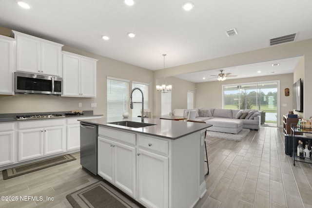 kitchen featuring appliances with stainless steel finishes, sink, an island with sink, and white cabinetry