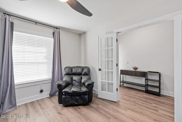 living area with ceiling fan, light hardwood / wood-style floors, french doors, and a textured ceiling