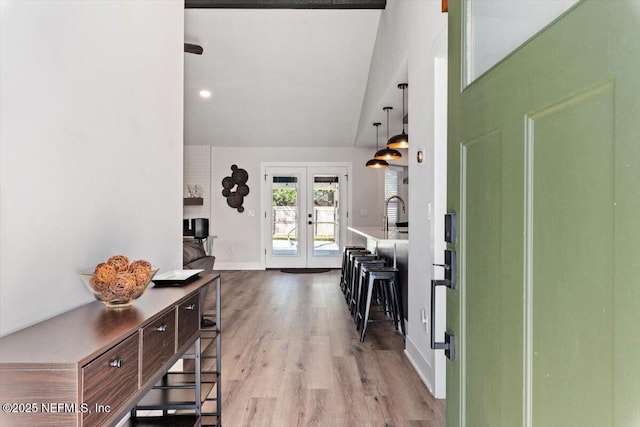 foyer featuring vaulted ceiling, light hardwood / wood-style floors, and french doors