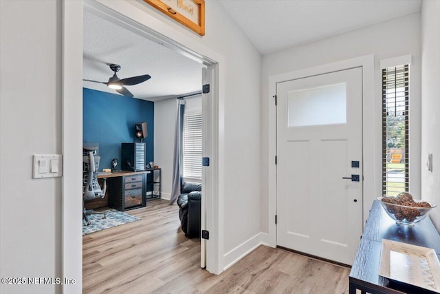 foyer featuring ceiling fan, light hardwood / wood-style floors, and a textured ceiling