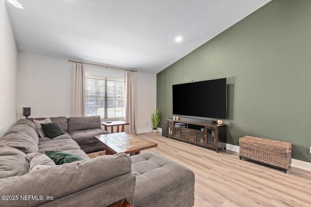 living room with lofted ceiling, a textured ceiling, and light wood-type flooring