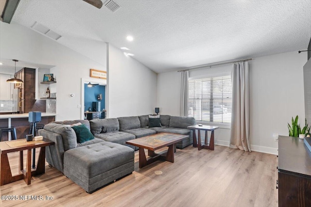 living room with vaulted ceiling, light wood-type flooring, a textured ceiling, and ceiling fan