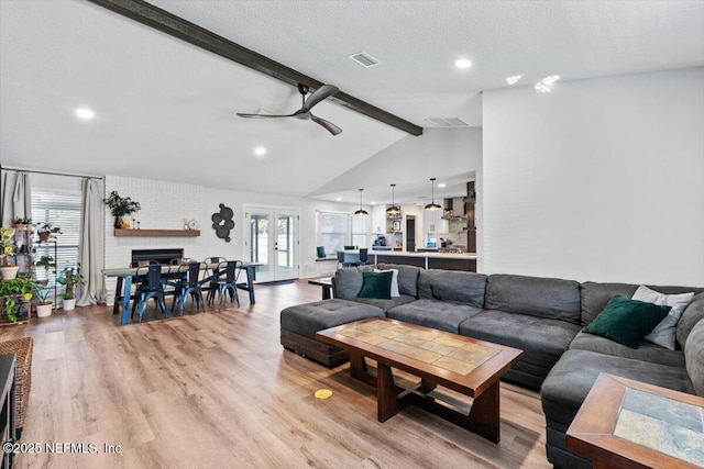 living room with light hardwood / wood-style flooring, ceiling fan, vaulted ceiling with beams, a textured ceiling, and french doors