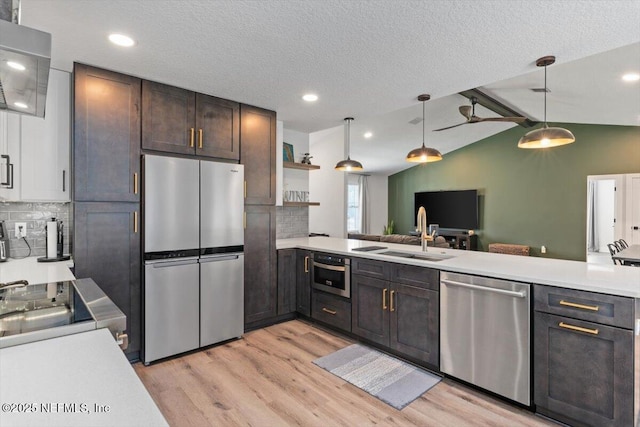 kitchen featuring appliances with stainless steel finishes, pendant lighting, sink, dark brown cabinets, and light hardwood / wood-style flooring