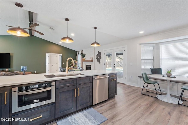 kitchen featuring french doors, sink, decorative light fixtures, stainless steel appliances, and light hardwood / wood-style floors